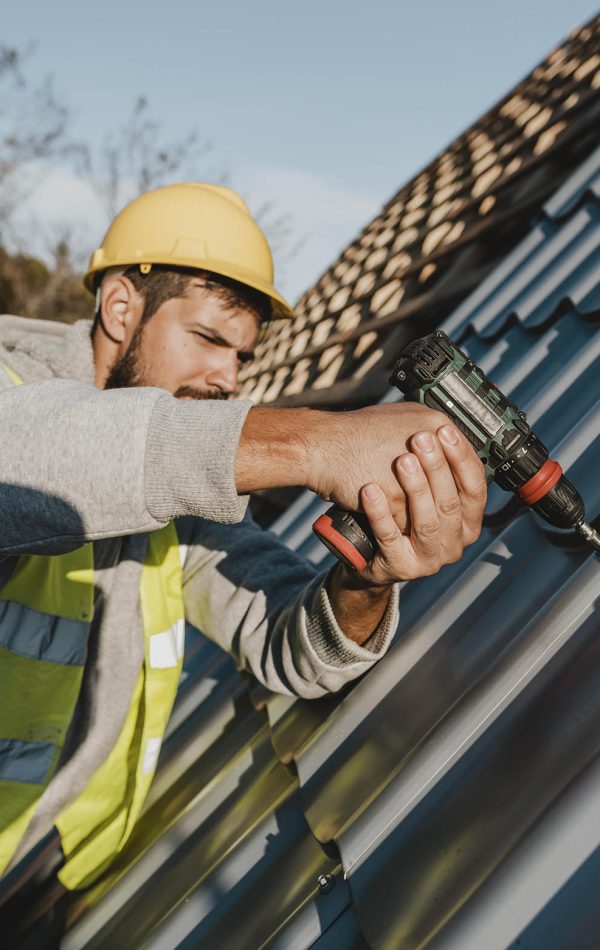 side-view-man-working-roof-with-drill